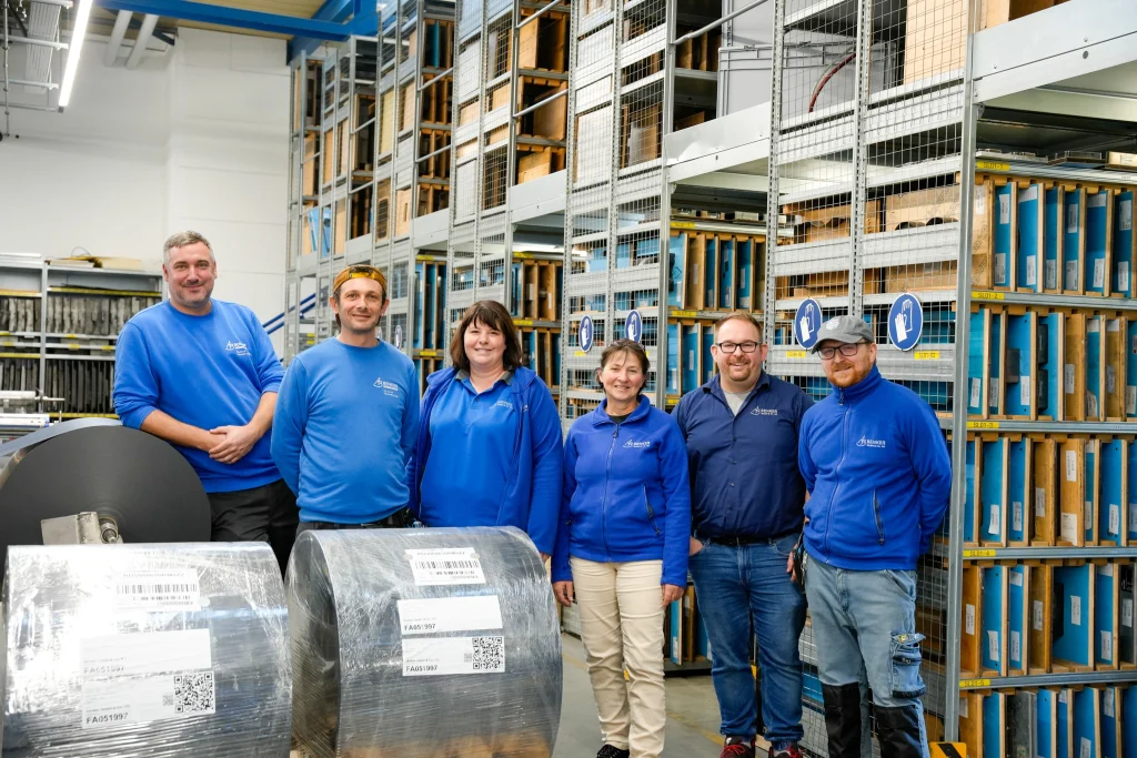 Sechs Mitarbeiterinnen und Mitarbeiter von Benker im Materiallager vor Folienrollen
